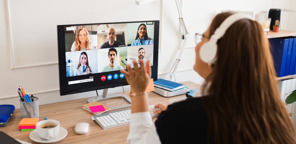 Eine Frau, die an ihrem Computer einen Videochat führt und sich mit anderen zu einem virtuellen Treffen trifft.