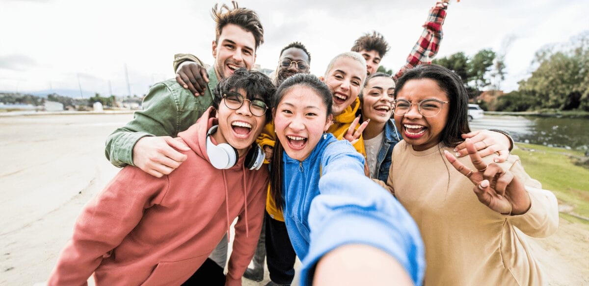 Eine Gruppe junger Menschen, die lächelnd zusammen für ein Selfie posieren und einen Moment der Freude und Freundschaft festhalten.